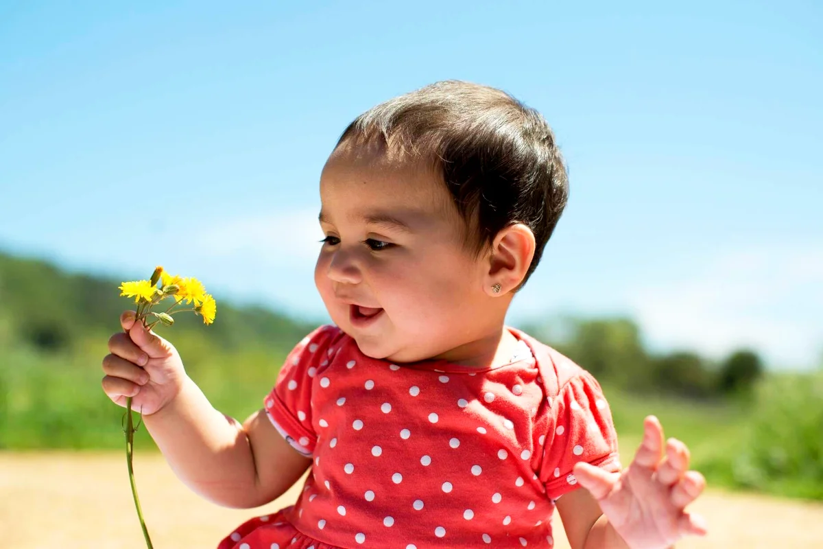 Smiling Girl Holding Yellow Flowers Against Sky