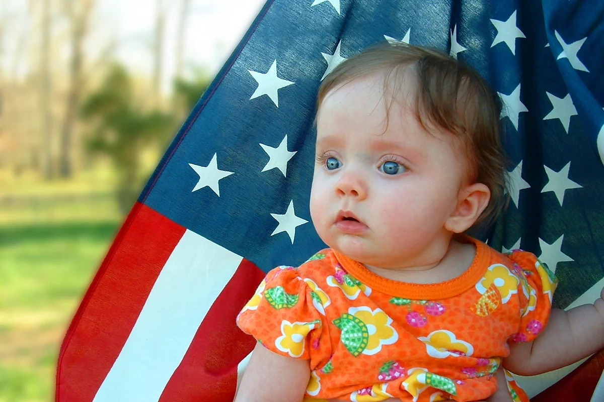 Baby girl sitting in front of an American Flag