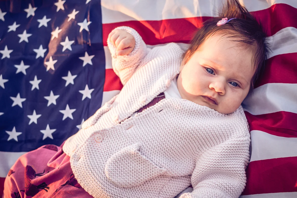 Baby lying on US flag on the grass in nature