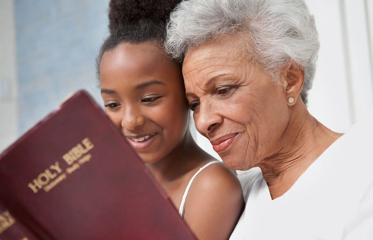 woman and granddaughter reading Bible together
