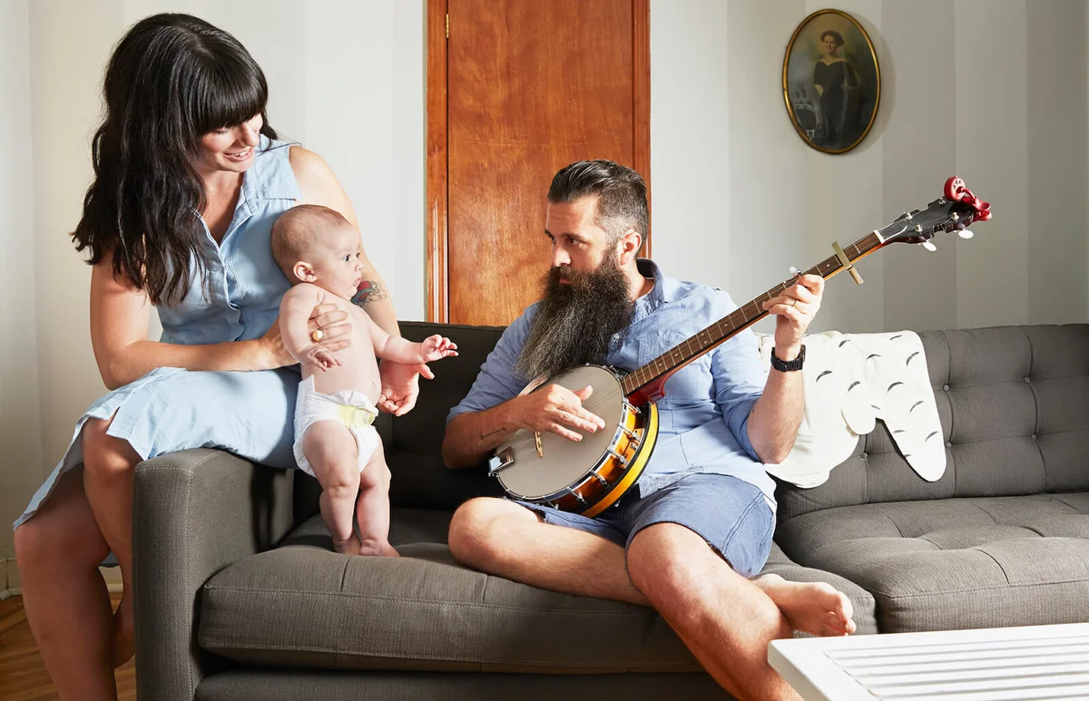 Father playing music to baby and wife at home