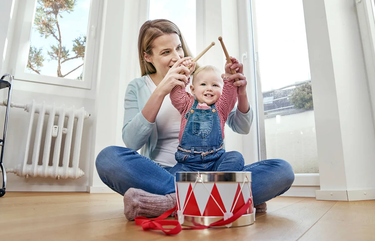 Mother and baby girl sitting on floor playing drums