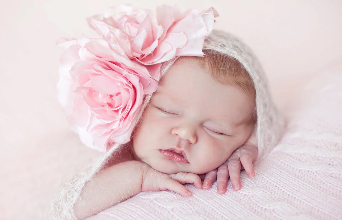 Newborn baby girl with pink wrap and pink rose hairband