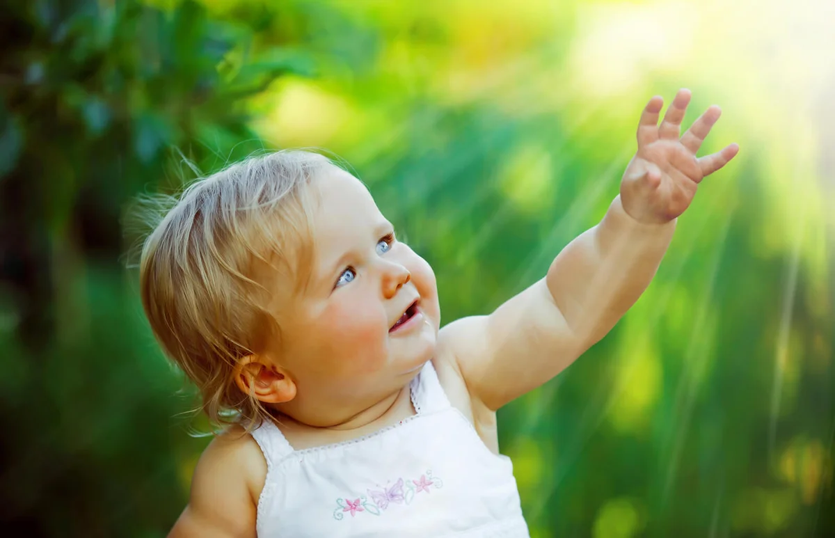 Smiling baby reaching into the light