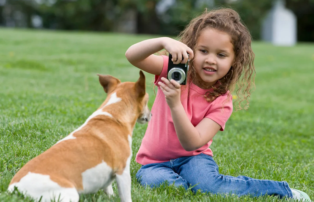 girl photographing dog