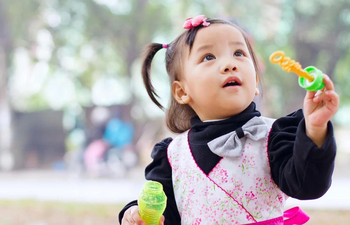Little girl playing with soup bubble maker