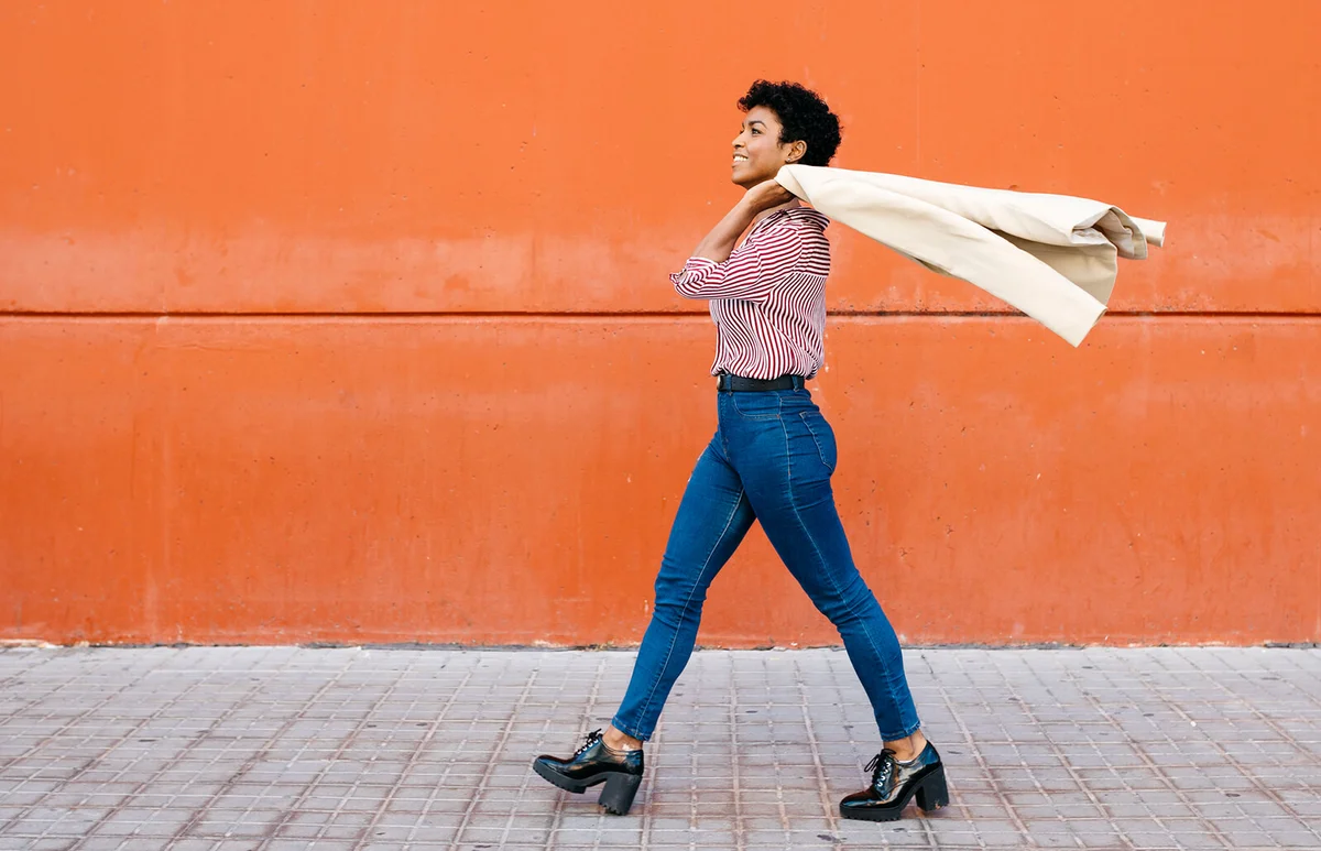 woman walking at a red wall in the background