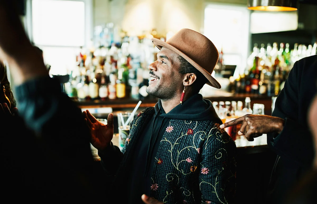 Laughing man in discussion with friends while sitting in bar