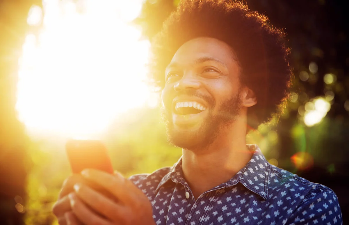 Smiling man looking up with smart phone