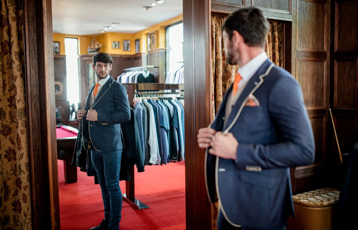 man admiring himself looking in a mirror in a menswear shop