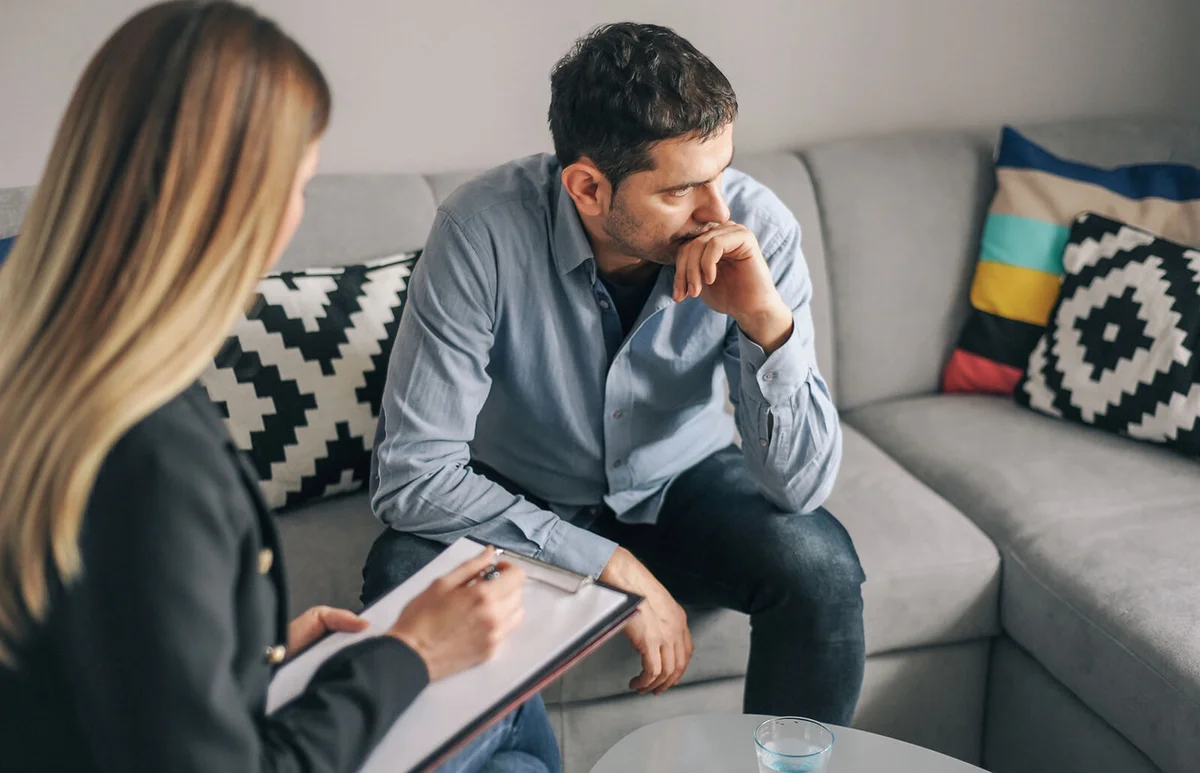 Young man talking to female therapist about his problems
