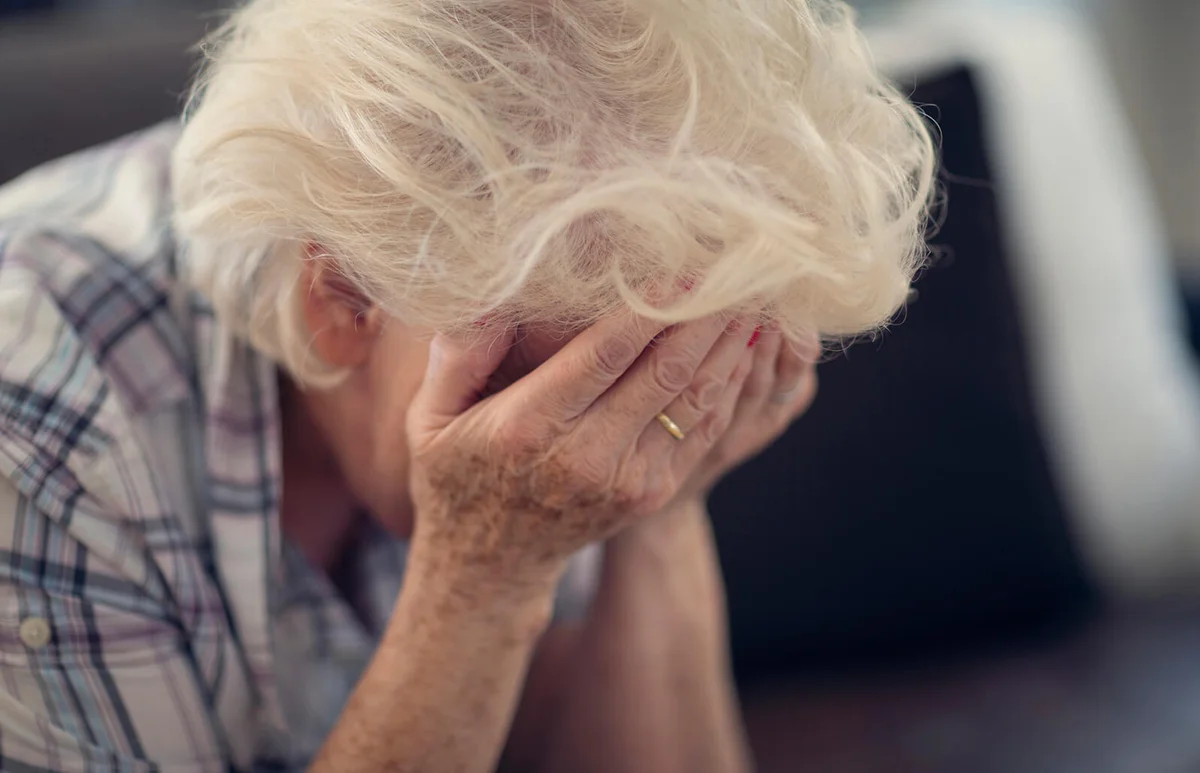 Senior woman holding head in hands in despair