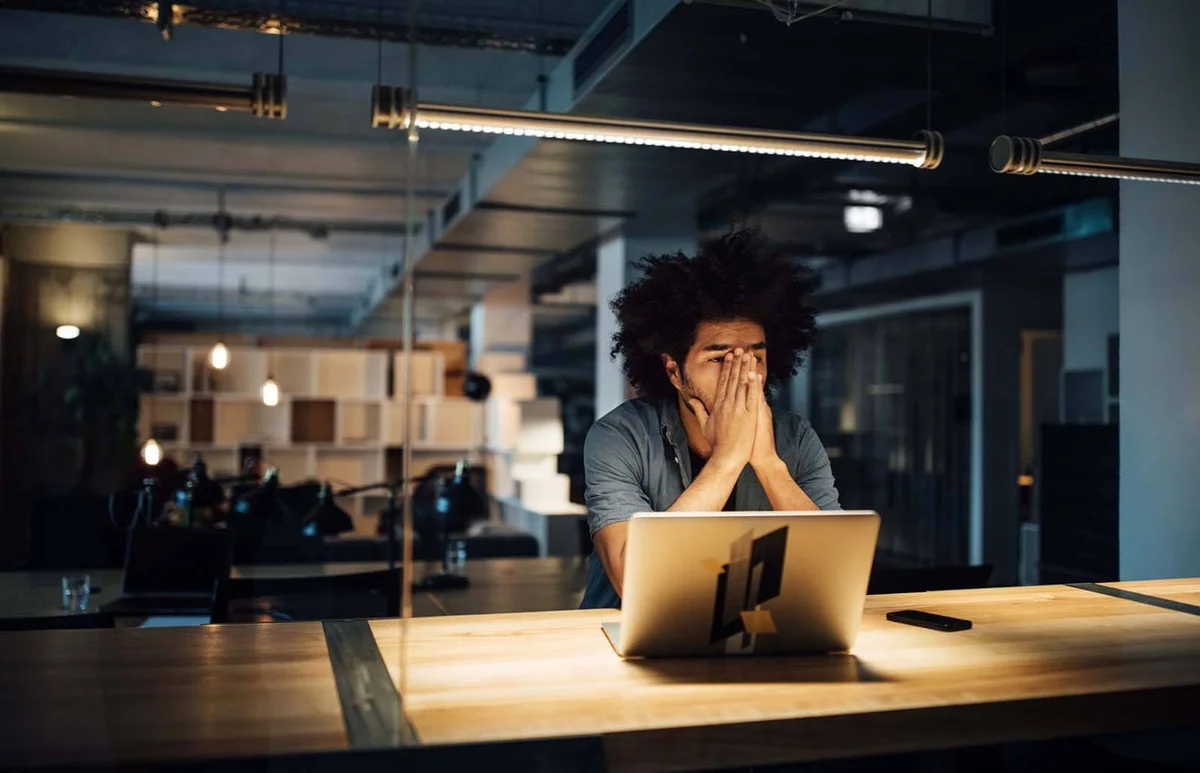 Tired businessman working on laptop at desk