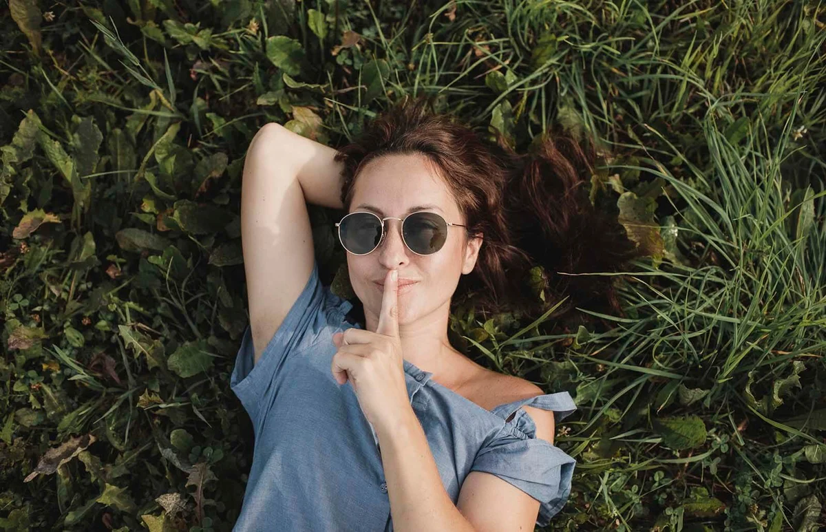 Portrait of smiling woman wearing sunglasses lying in grass
