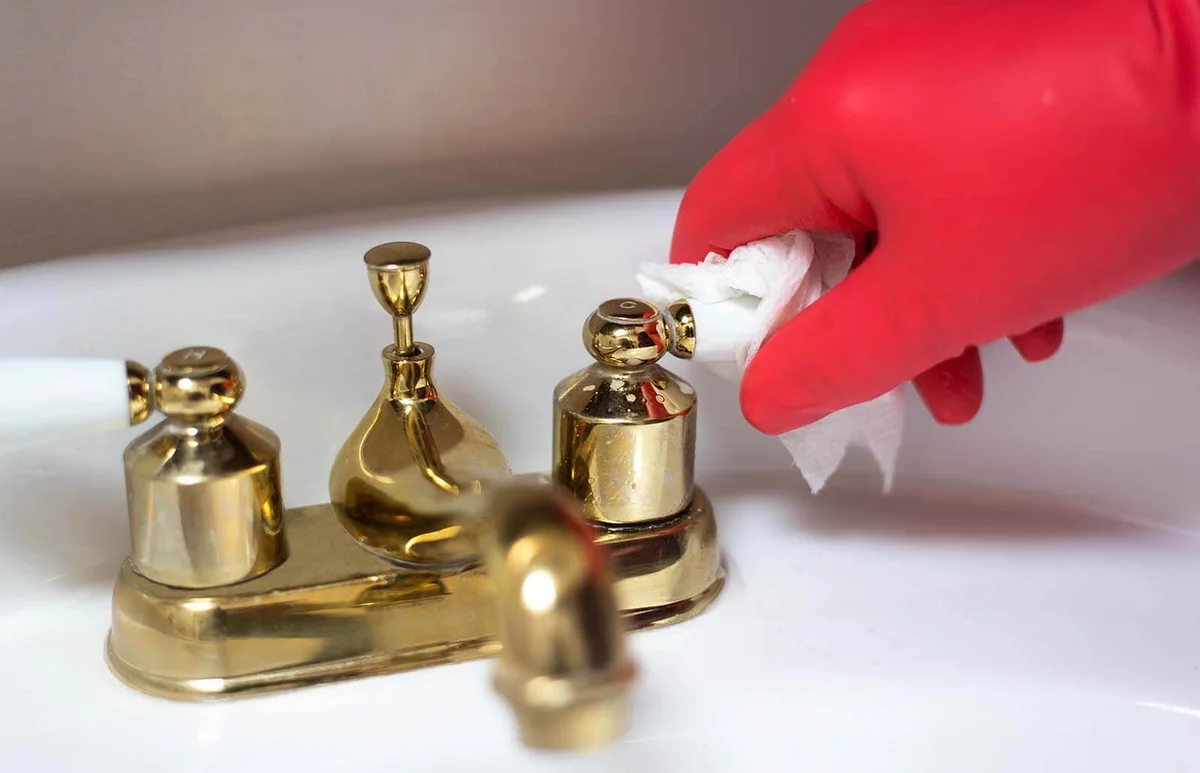 Hand in Red Plastic Gloves Cleaning Bath Faucet