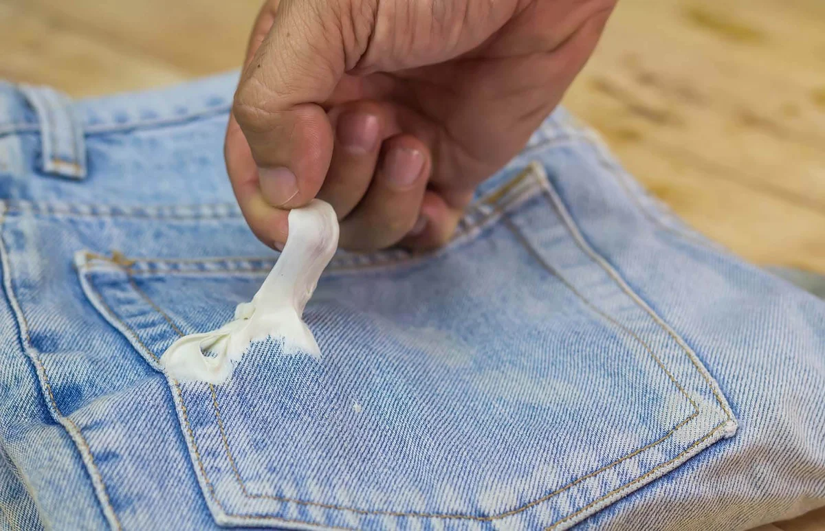 Gum sticking on jean with holding hand to remove