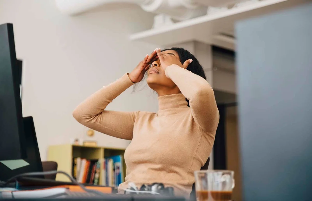 Frustrated woman with head in hands sitting in creative office