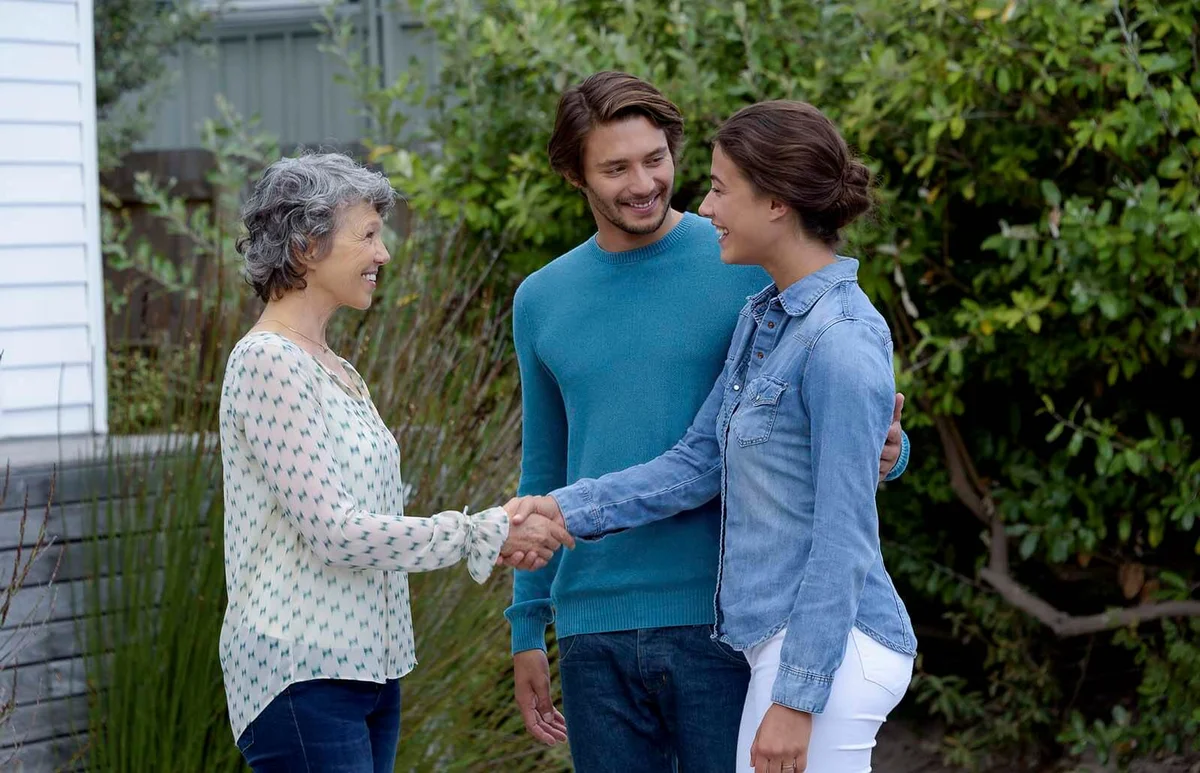 Happy mature woman meet with young couple outside