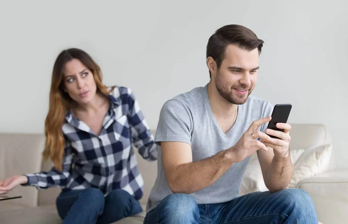 wife arguing with obsessed husband holding phone