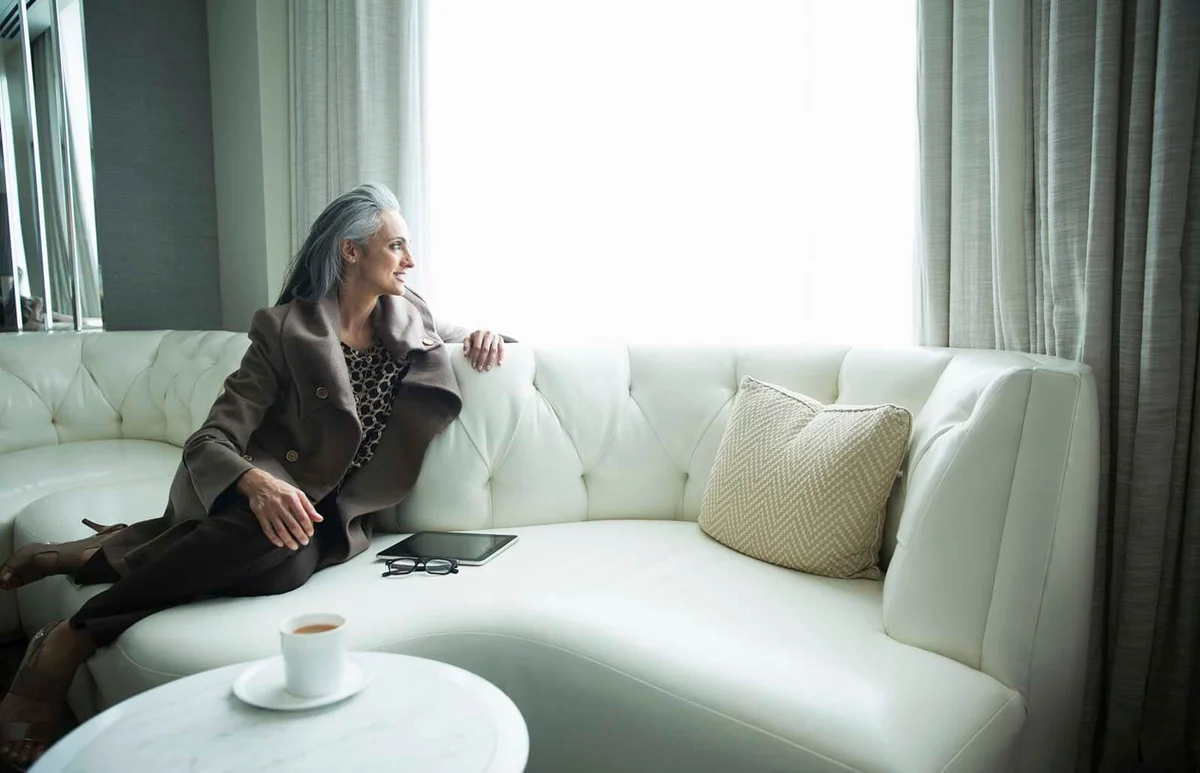 Portrait of mature woman reclining on white luxury sofa
