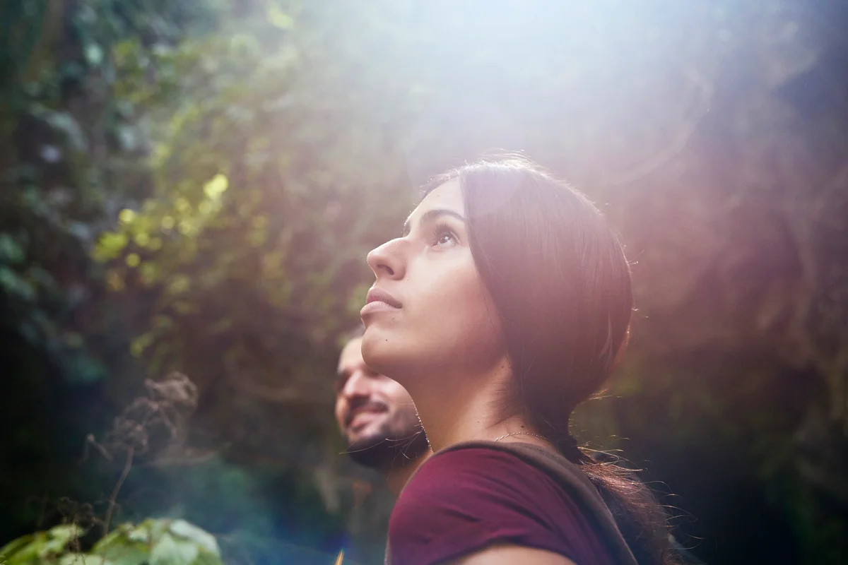 Female hiker with boyfriend in a forest looking up