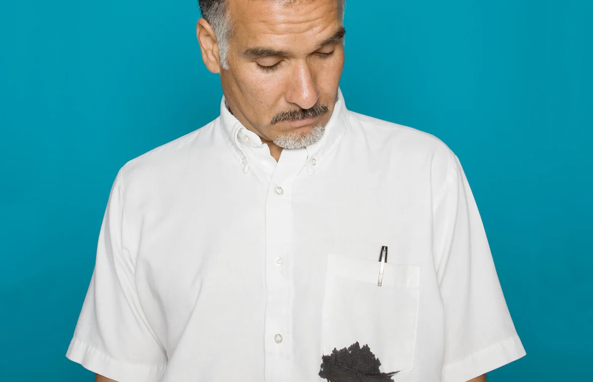Man looking at ink stain on shirt