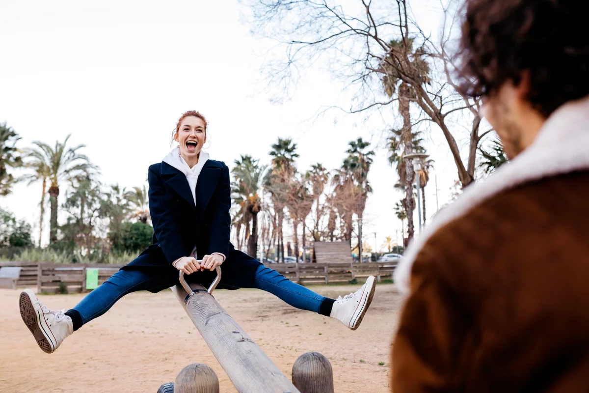Exuberant couple on a seesaw at a playground