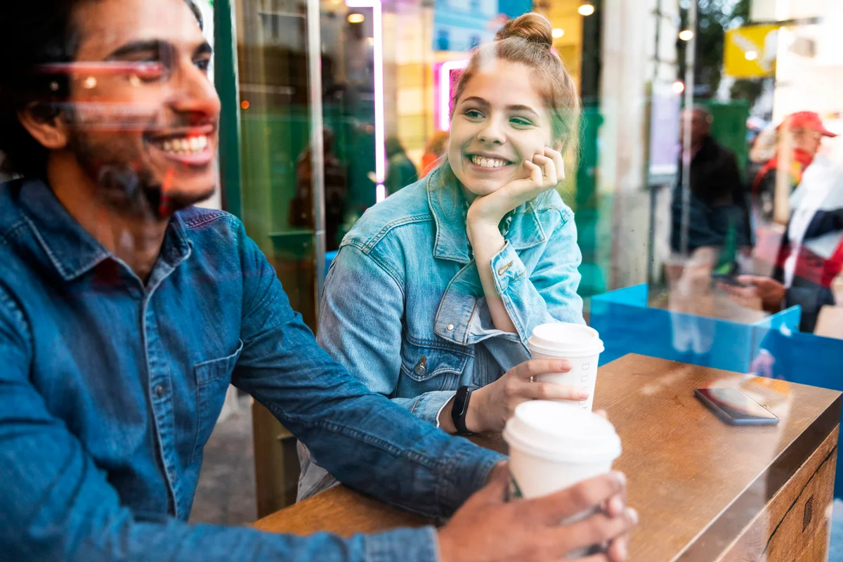 Smiling young woman in a coffee shop looking at young man