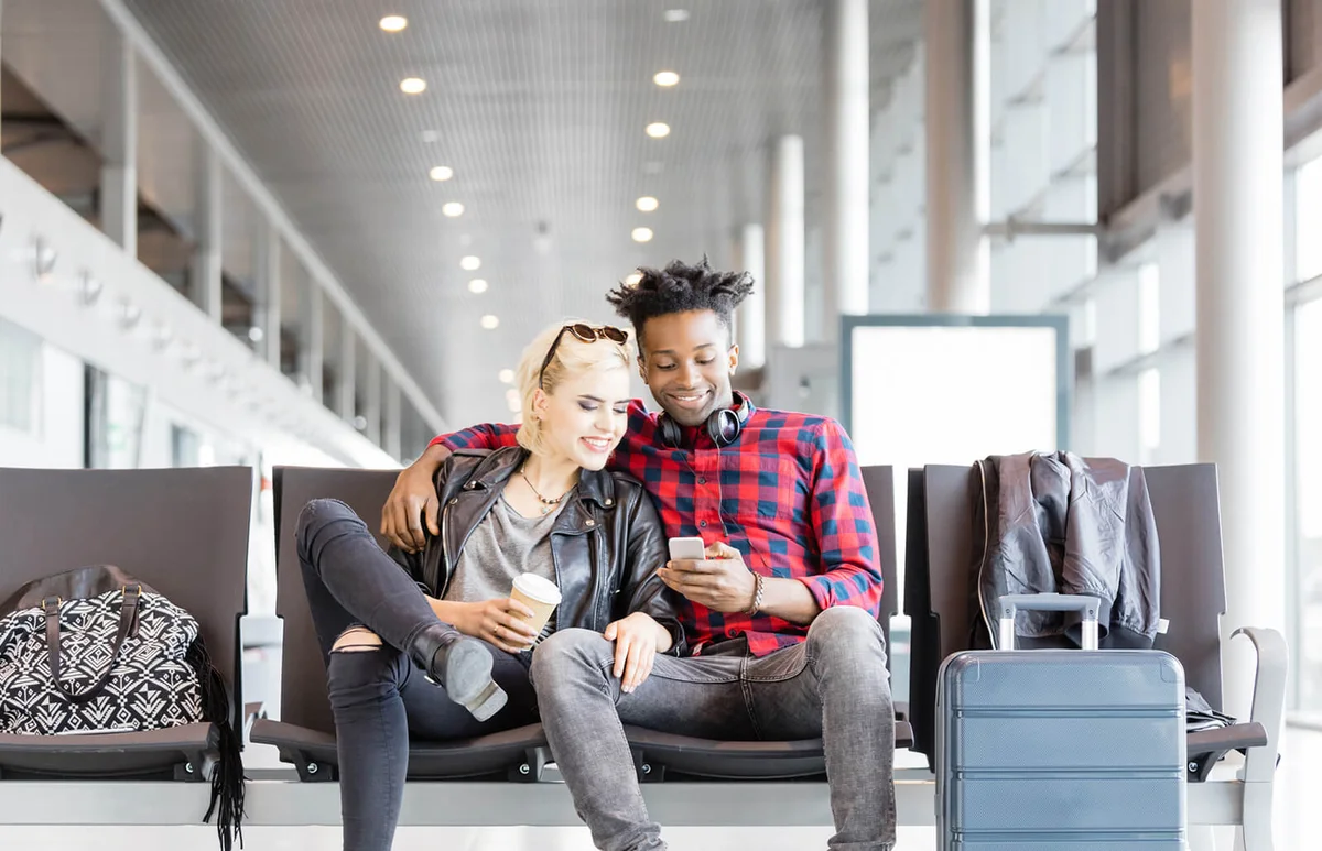 couple using mobile phone in airport lounge