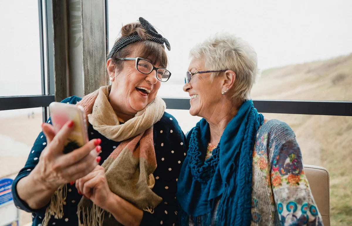 Senior female friends catching up over coffee in a seaside cafe
