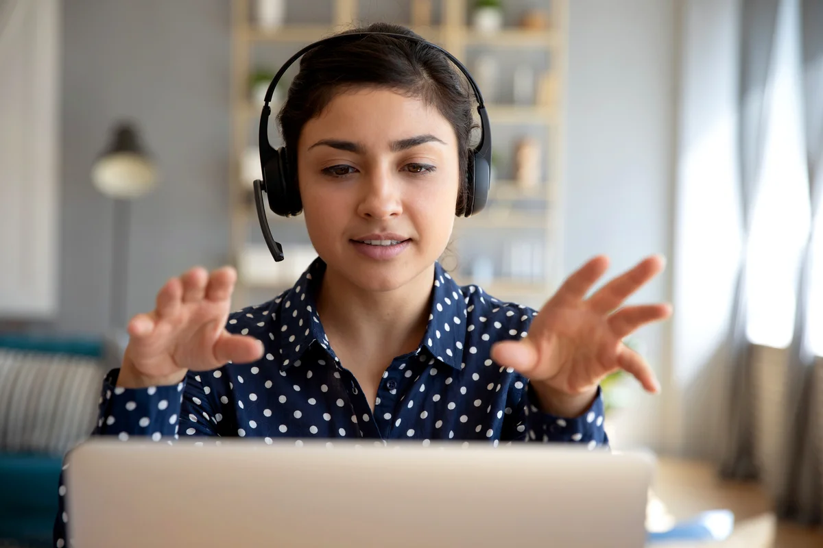 Woman wear wireless headset video calling on laptop