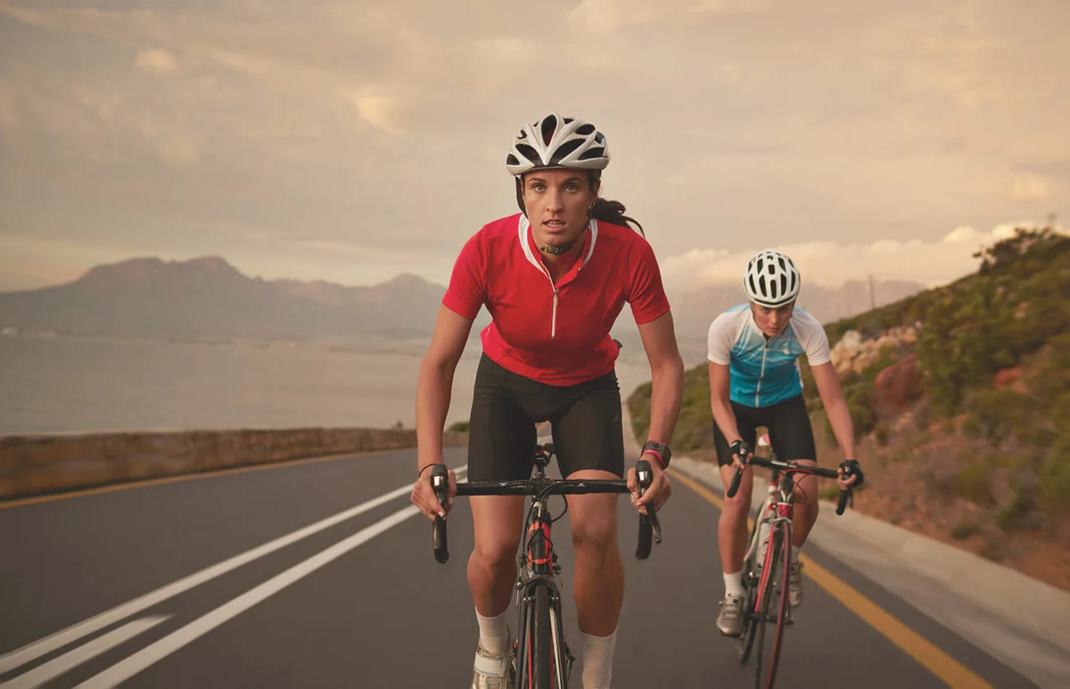 Professional female cyclists on road bikes at sunset