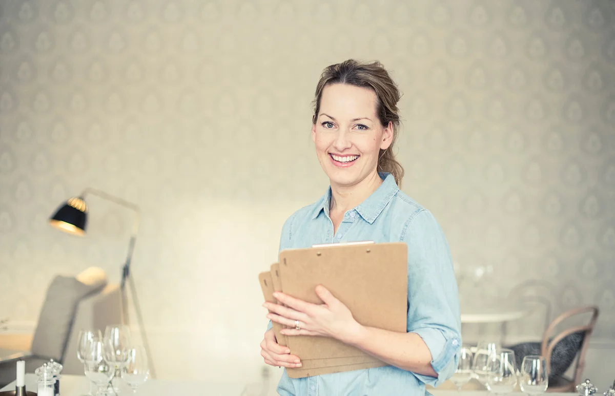 smiling female owner with clipboards in restaurant