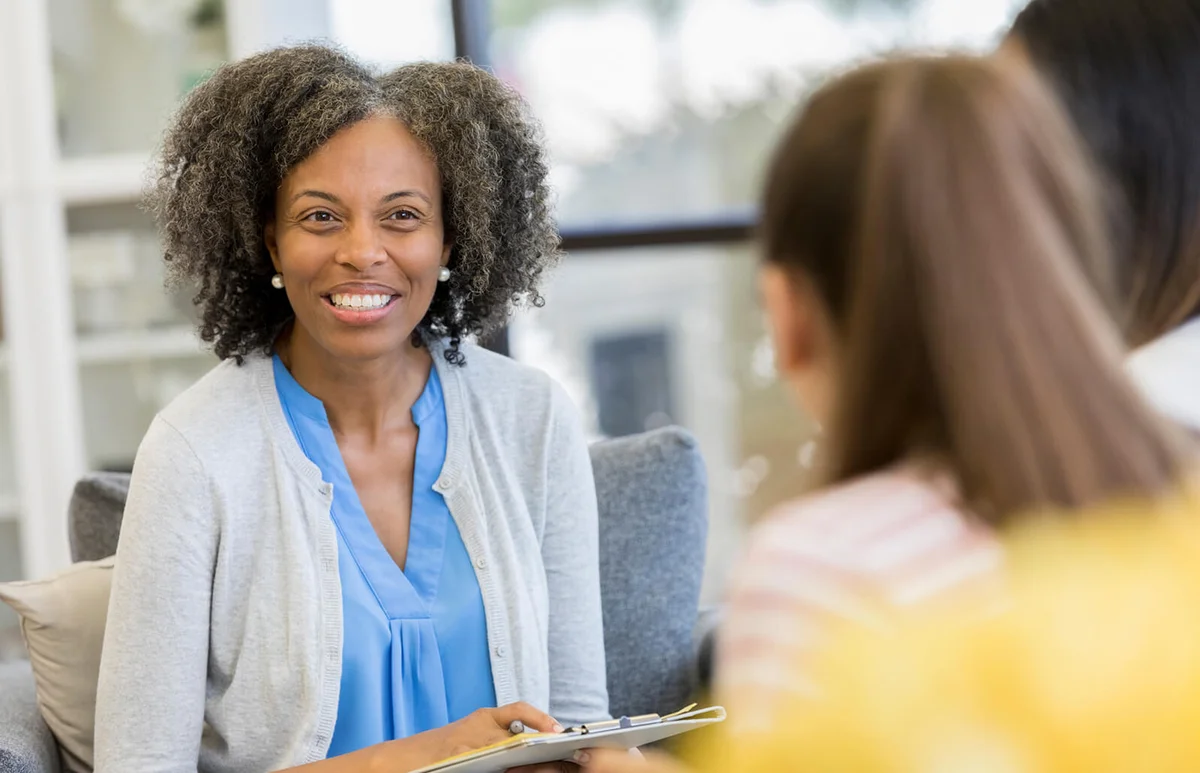 Cheerful high school guidance counselor talking with students