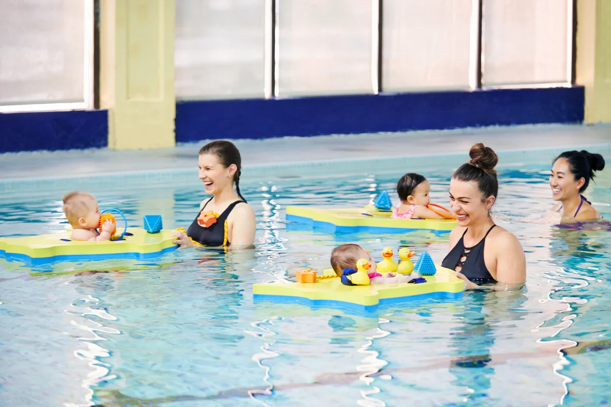 Shot of mothers enjoying themselves with their babies at swimming class