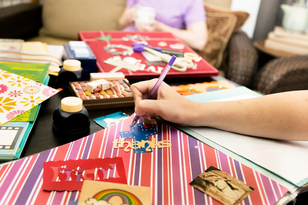 Woman considering arrangements, labels. Scrapbooking