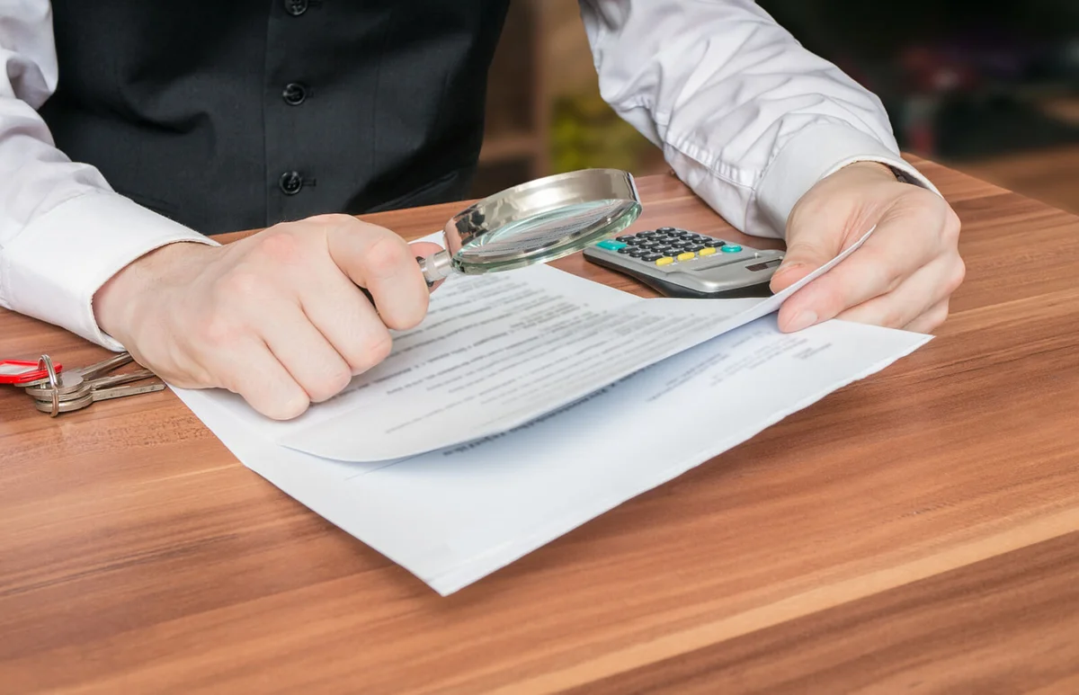 Man holds magnifying glass and is reading contract