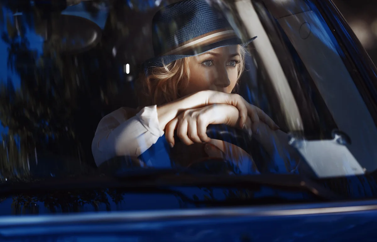 Woman with hat driving blue car