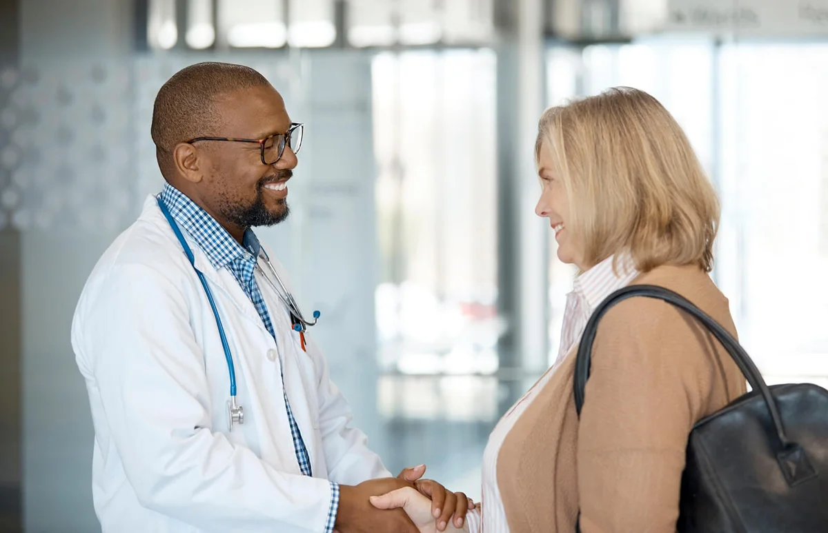 Smiling male doctor and woman shaking hands