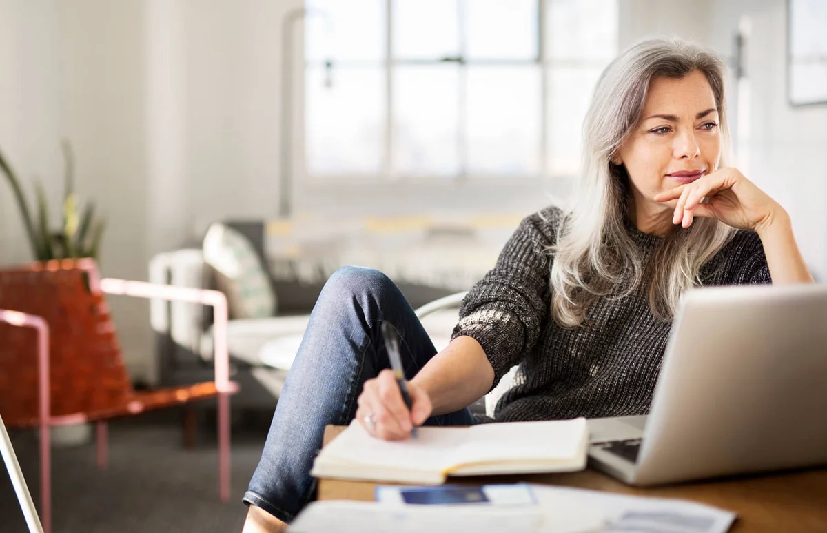 Mature woman writing in diary while working at home