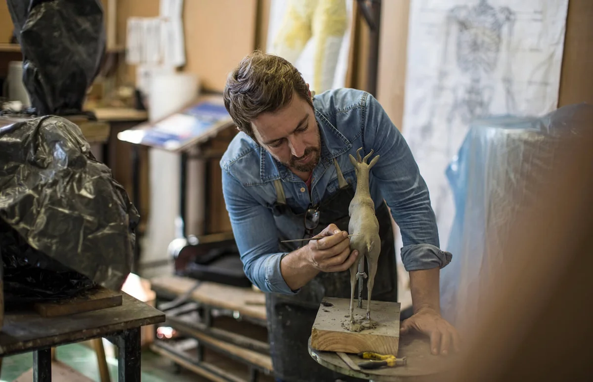 Sculptor working in studio on animal figurine
