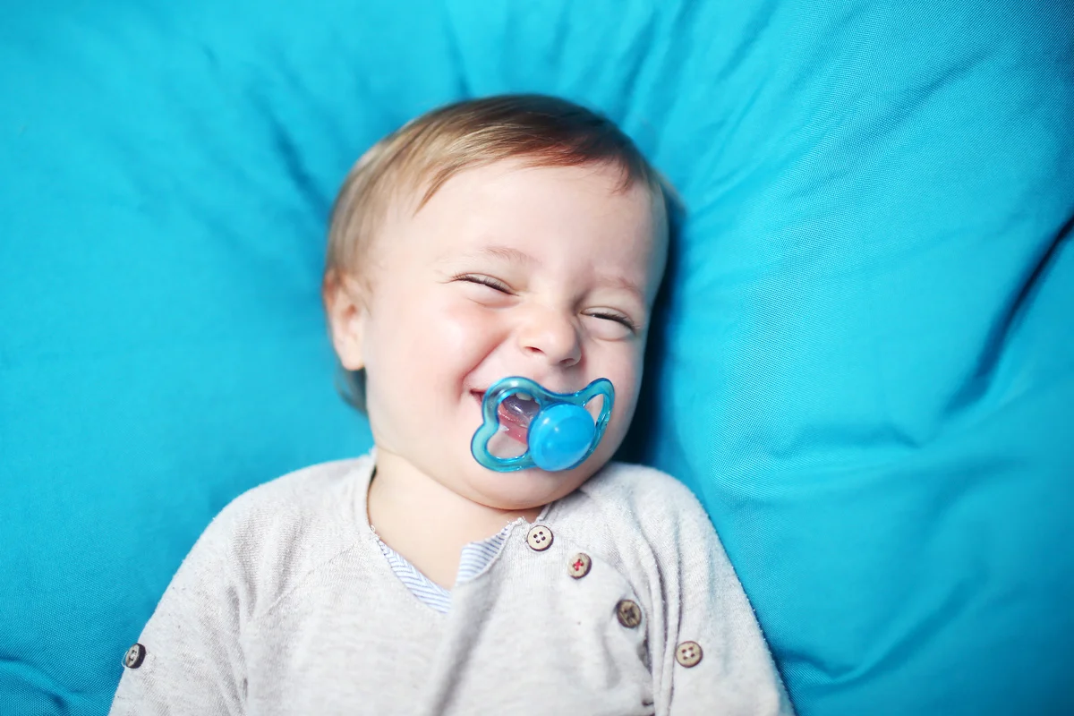 A 18 months old boy with a pacifier surrounded by blue