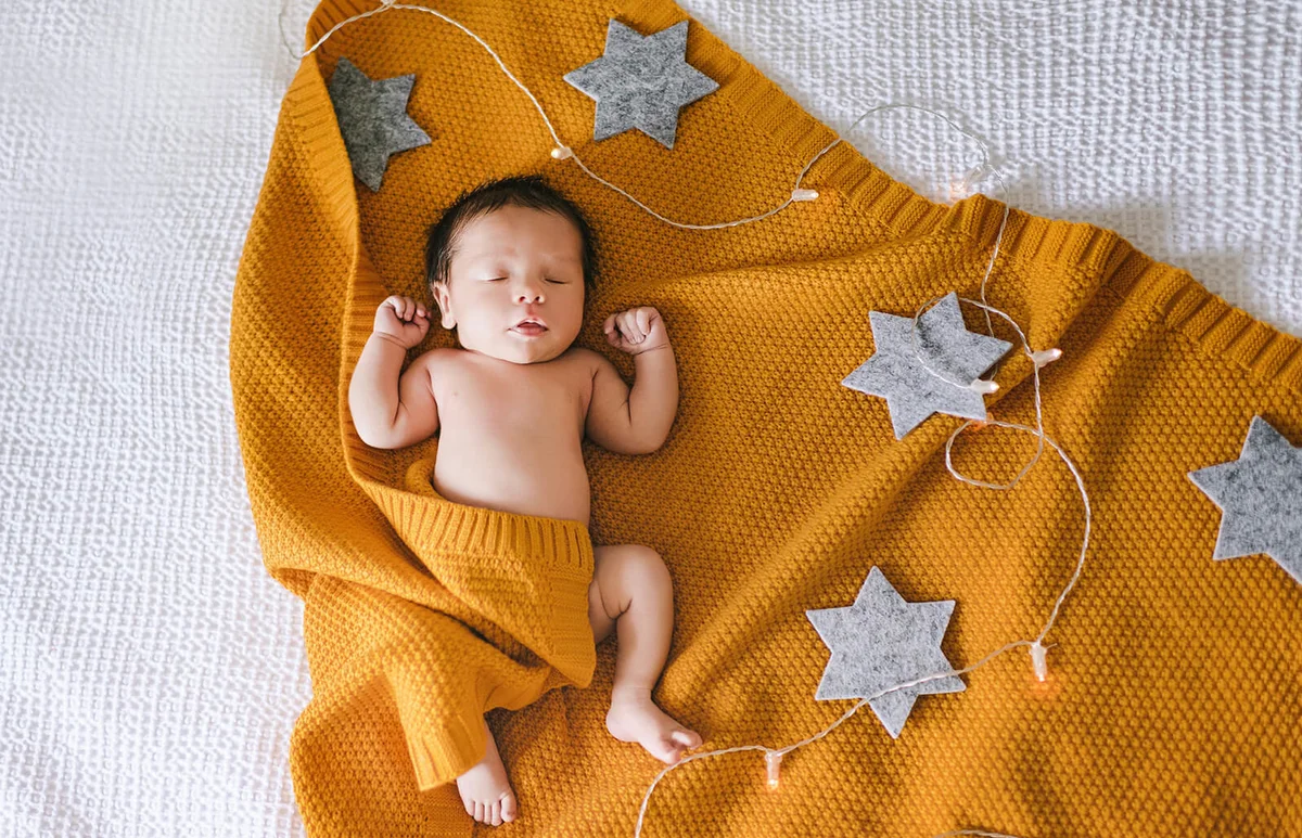 Cute newborn sleeping baby in yellow knitted blanket