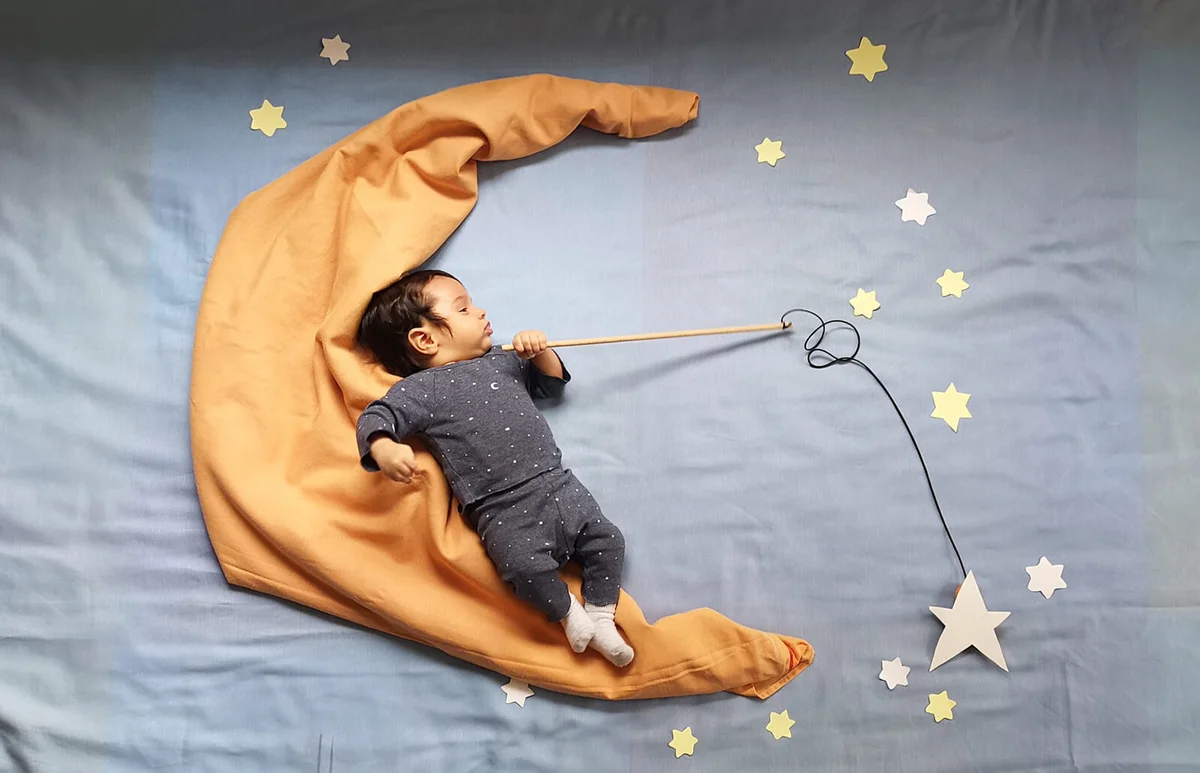 Baby Boy With Star Decorations Sleeping On Bed At Home