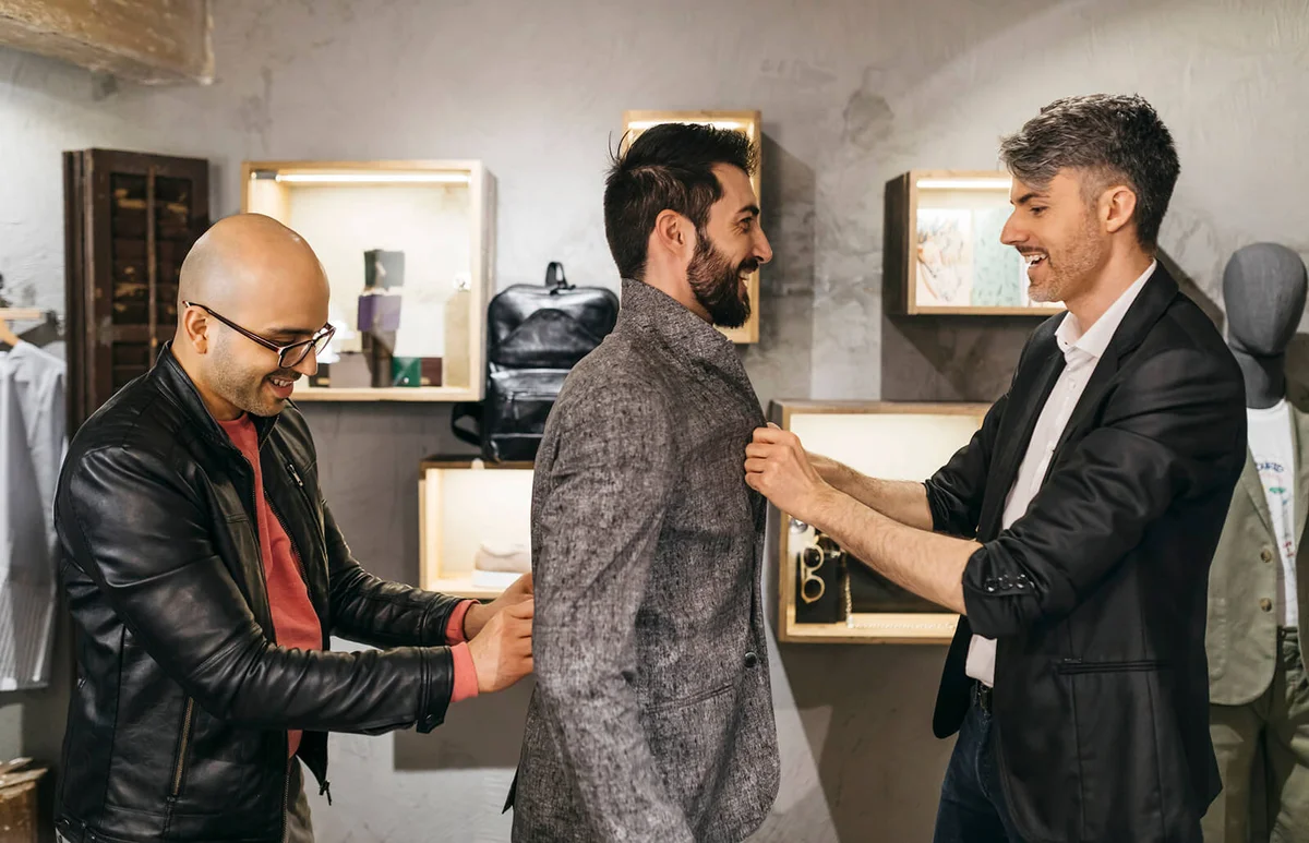 Two men working on new stylish look for handsome man in showroom