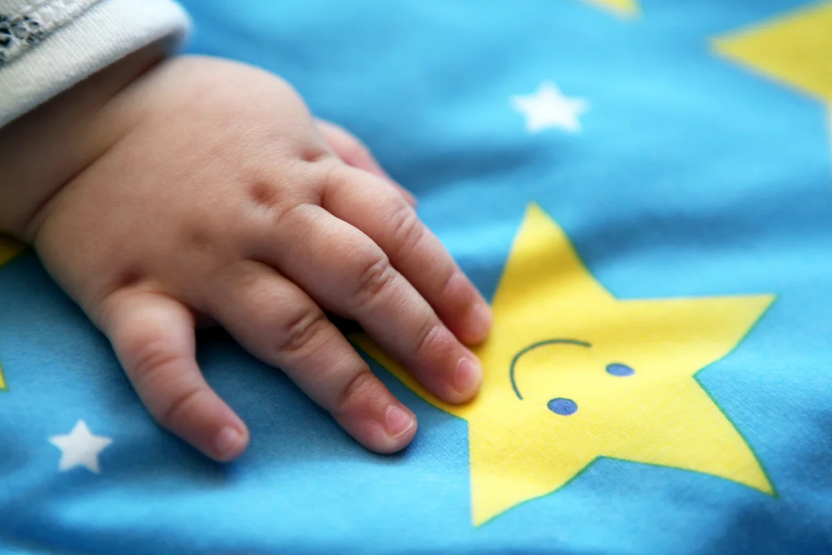Sleeping baby girl hand on a star