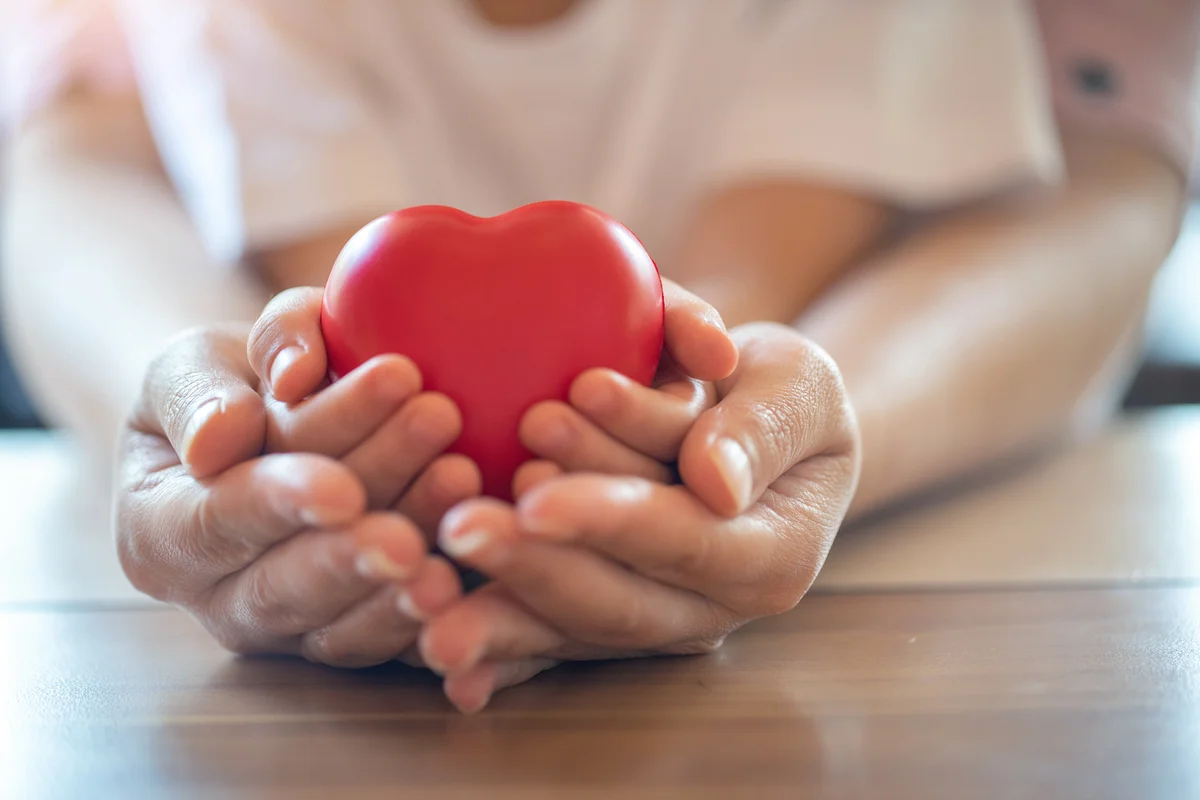 Adult and child hands holding red heart
