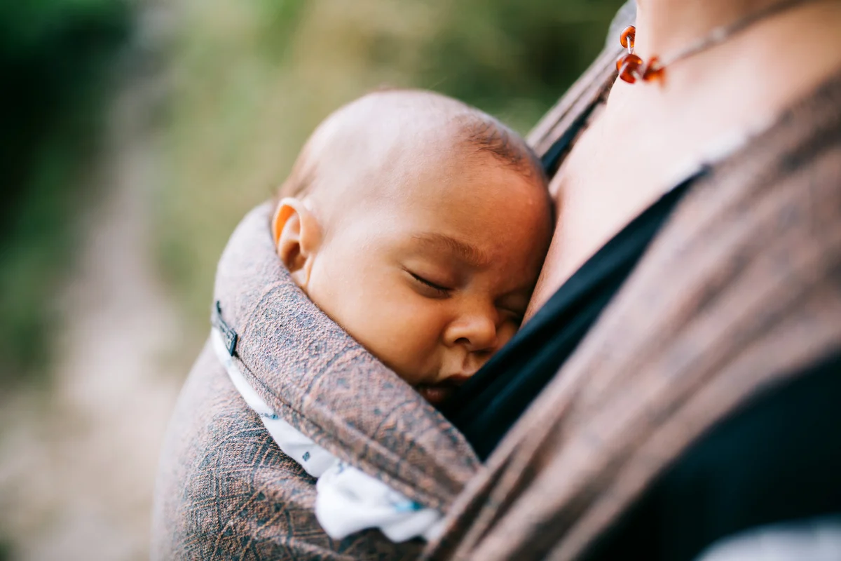 Mother Carrying Sleeping Daughter In Baby Carrier
