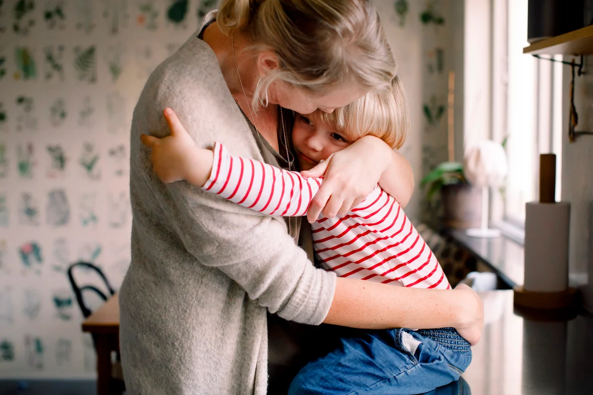 Loving daughter embracing mother while sitting on kitchen counter