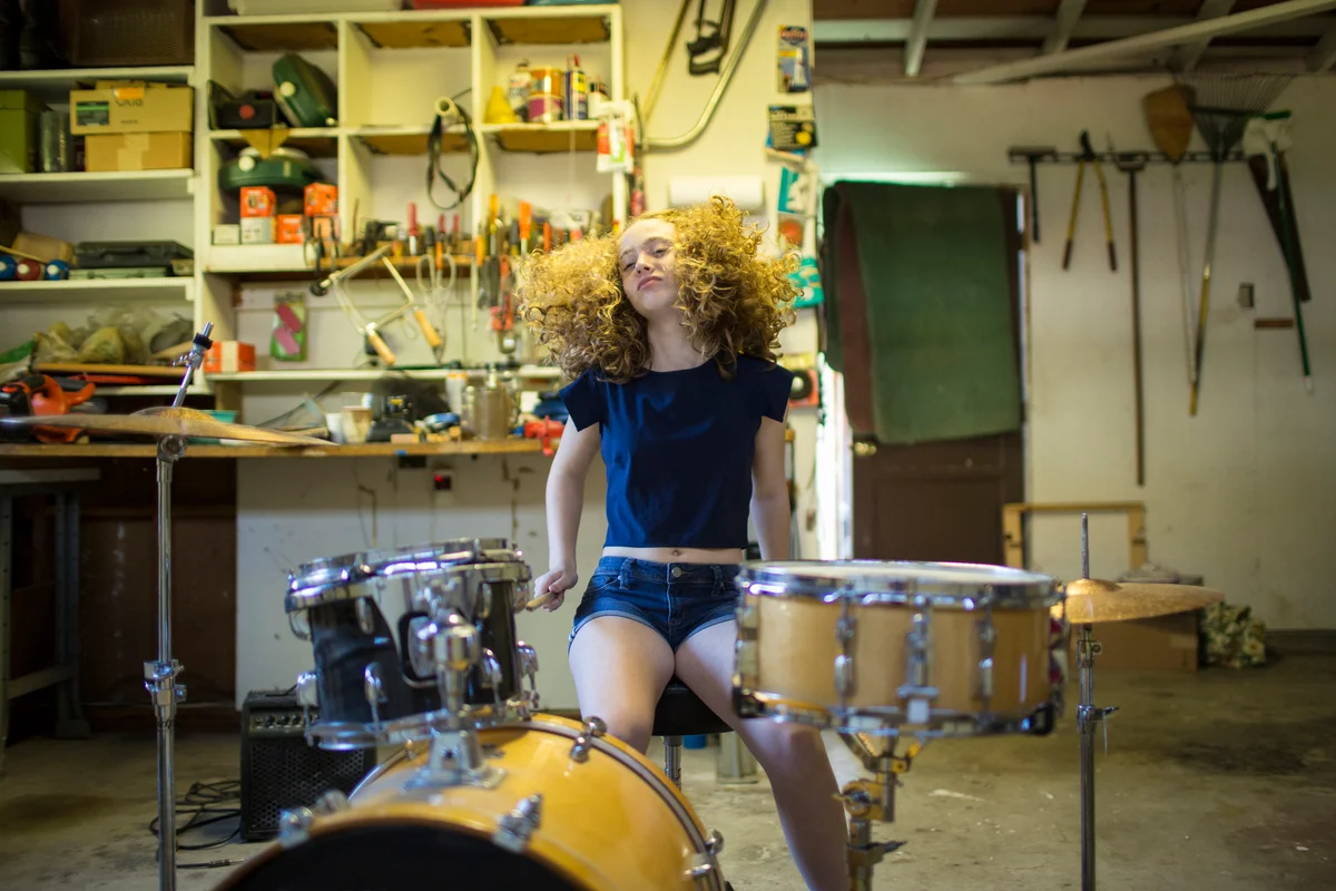 Teenage girl drumming in garage